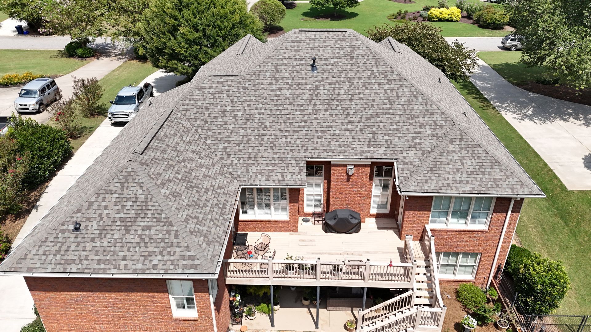 An aerial view of a large brick house with a gray roof.