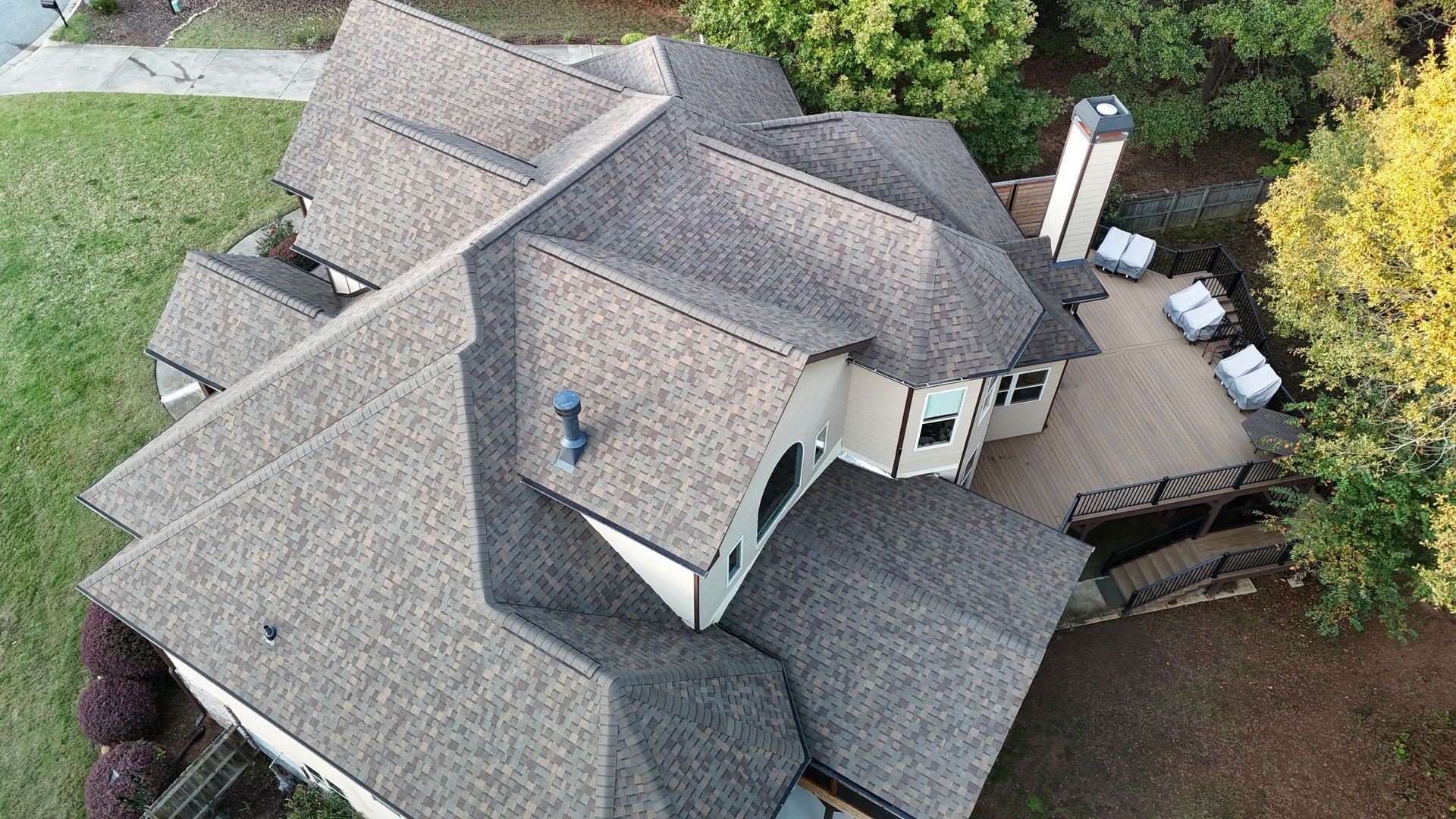 An aerial view of a large house with a roof and a deck.