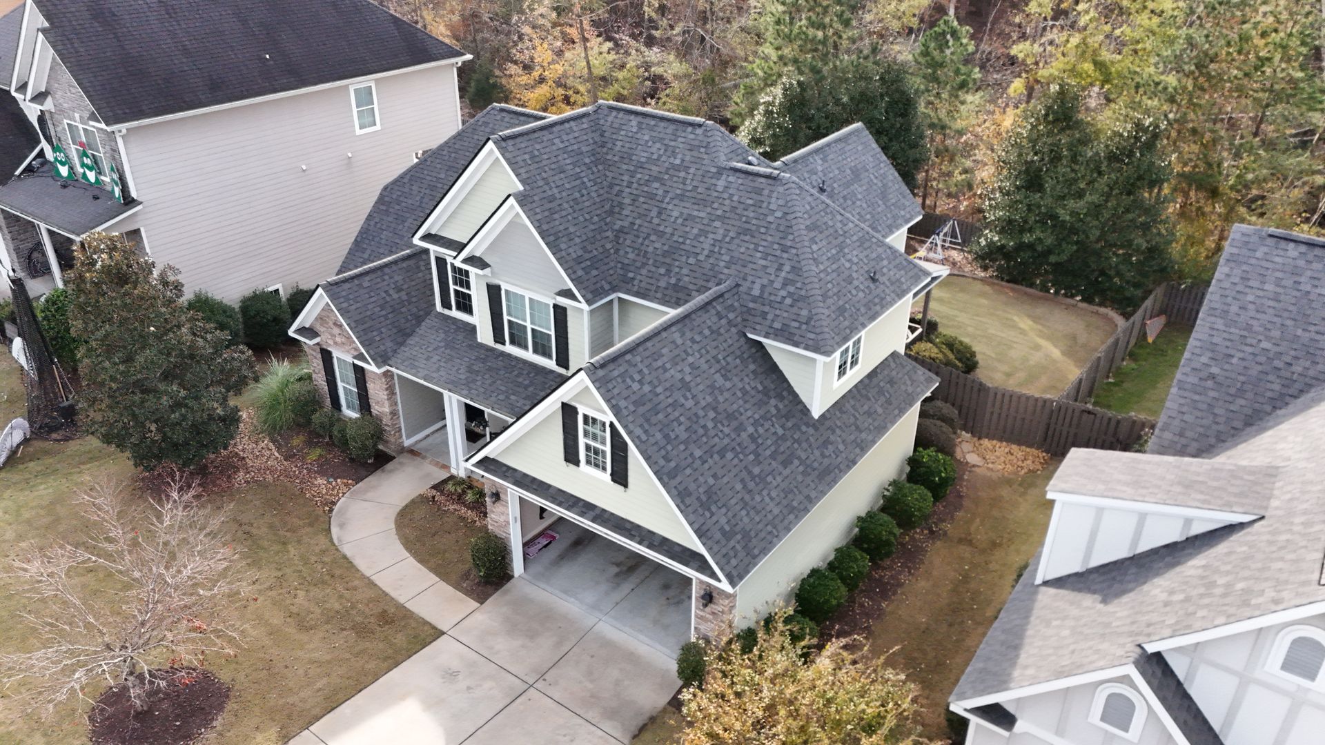 An aerial view of a house with a gray roof in a residential area.