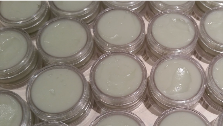 Small, clear jars filled with pale green cream, arranged closely together.