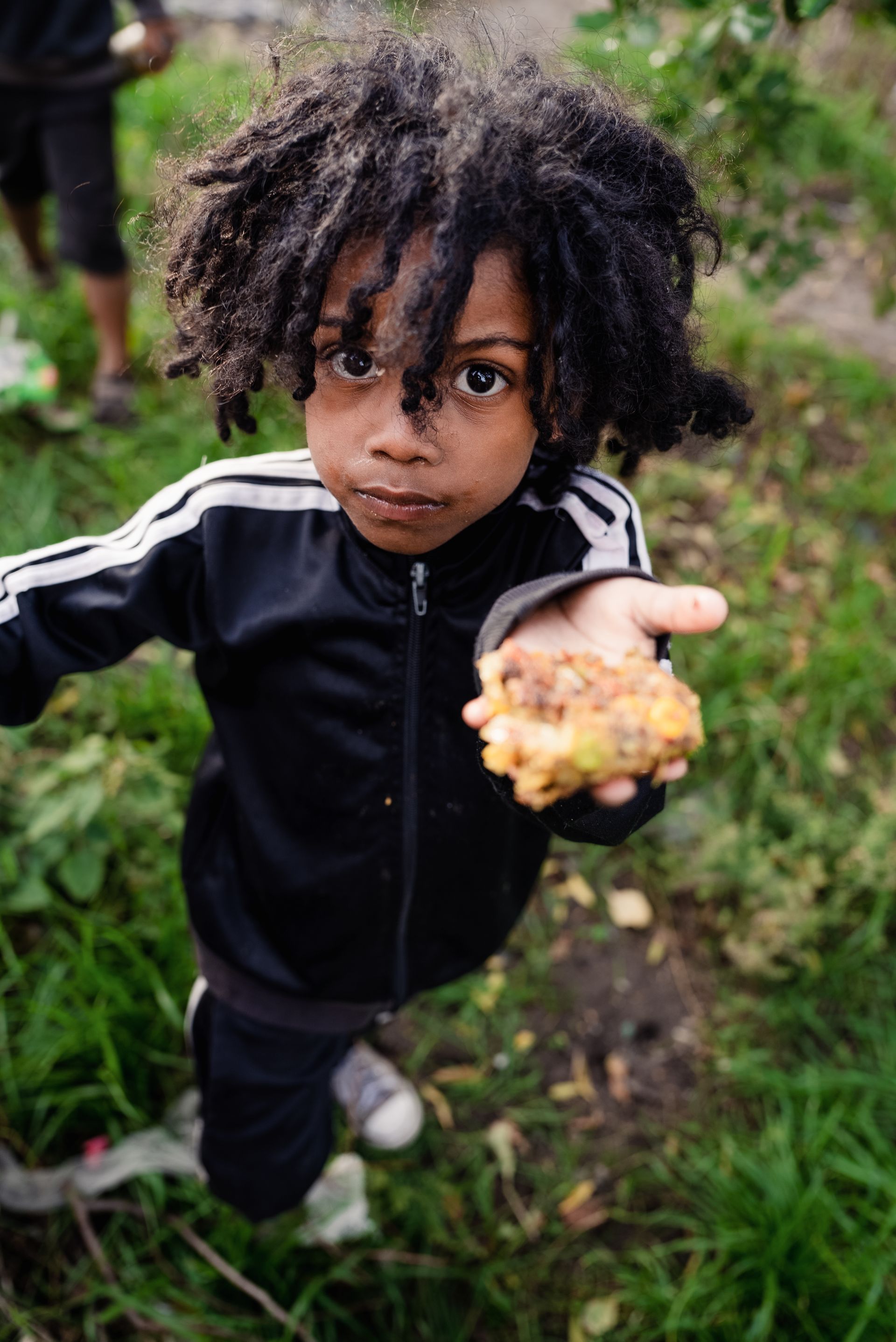 A young boy is holding a piece of food in his hand.