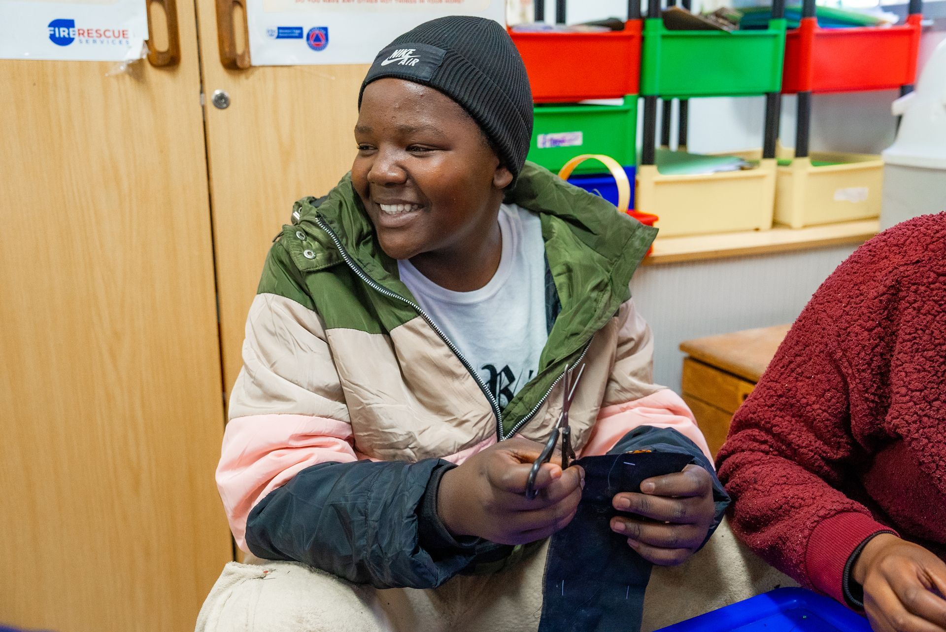 A young woman is sitting at a table holding a cell phone.