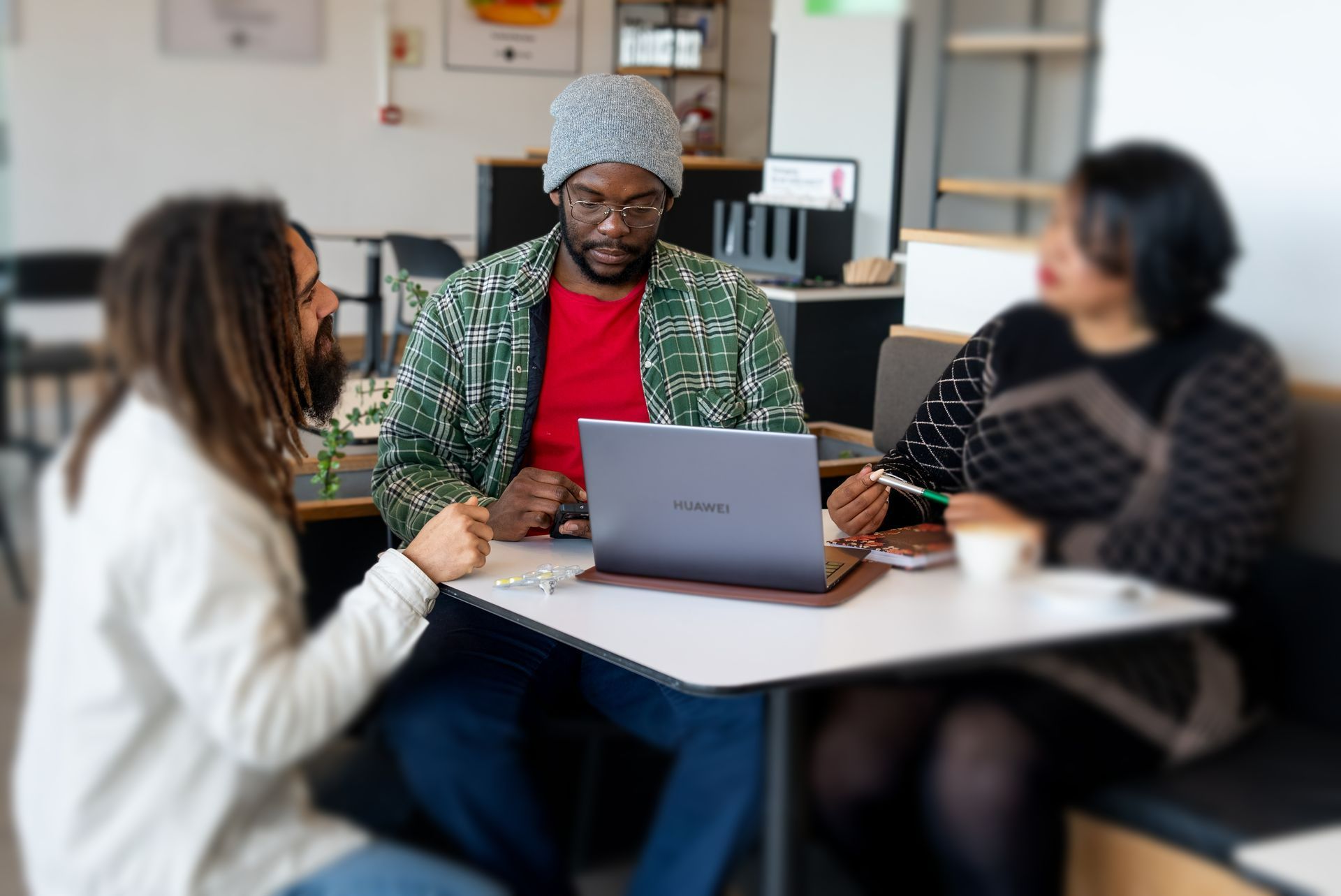A group of people are sitting around a table with a laptop.