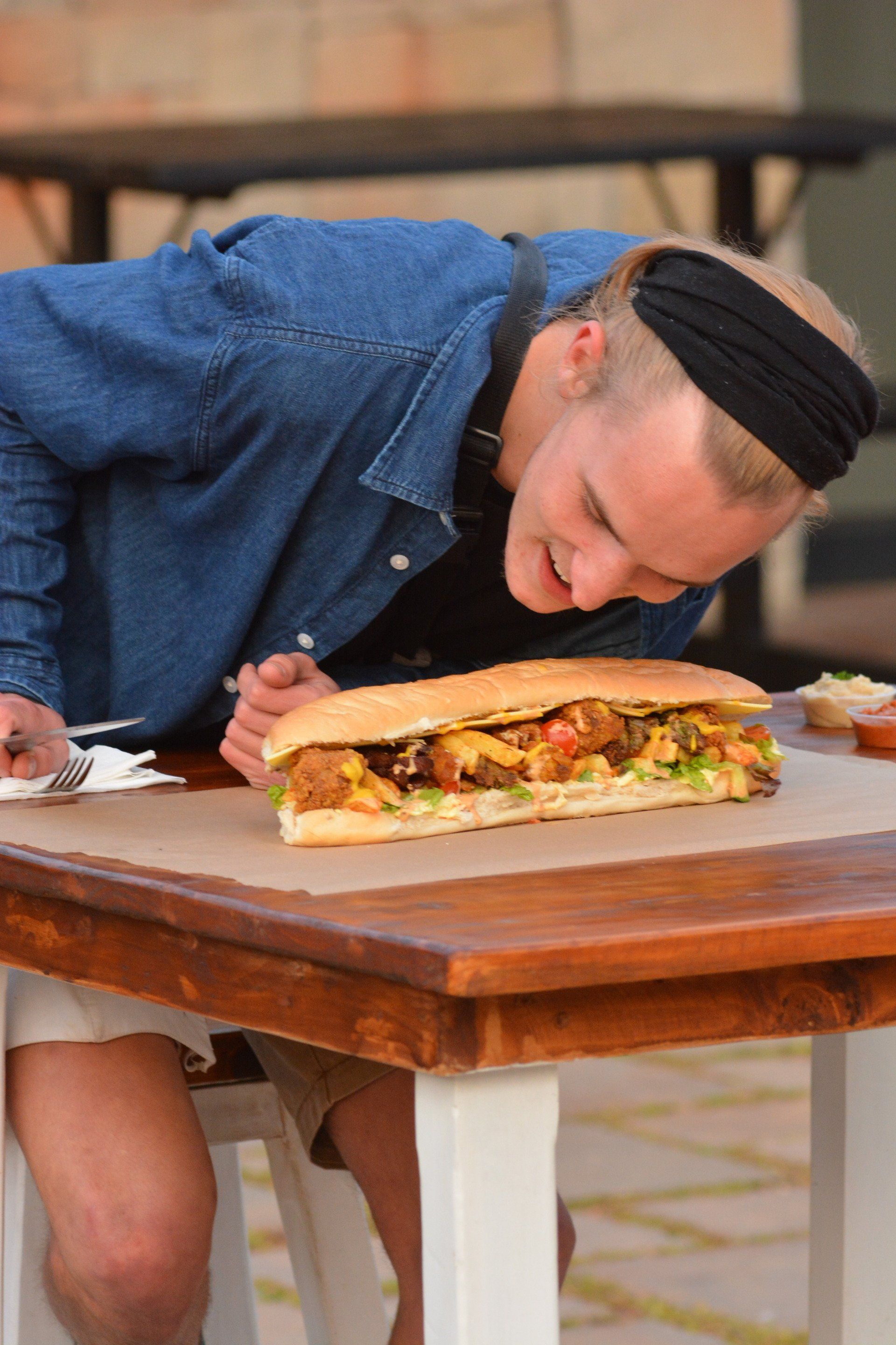 A man is sitting at a table eating a sandwich.