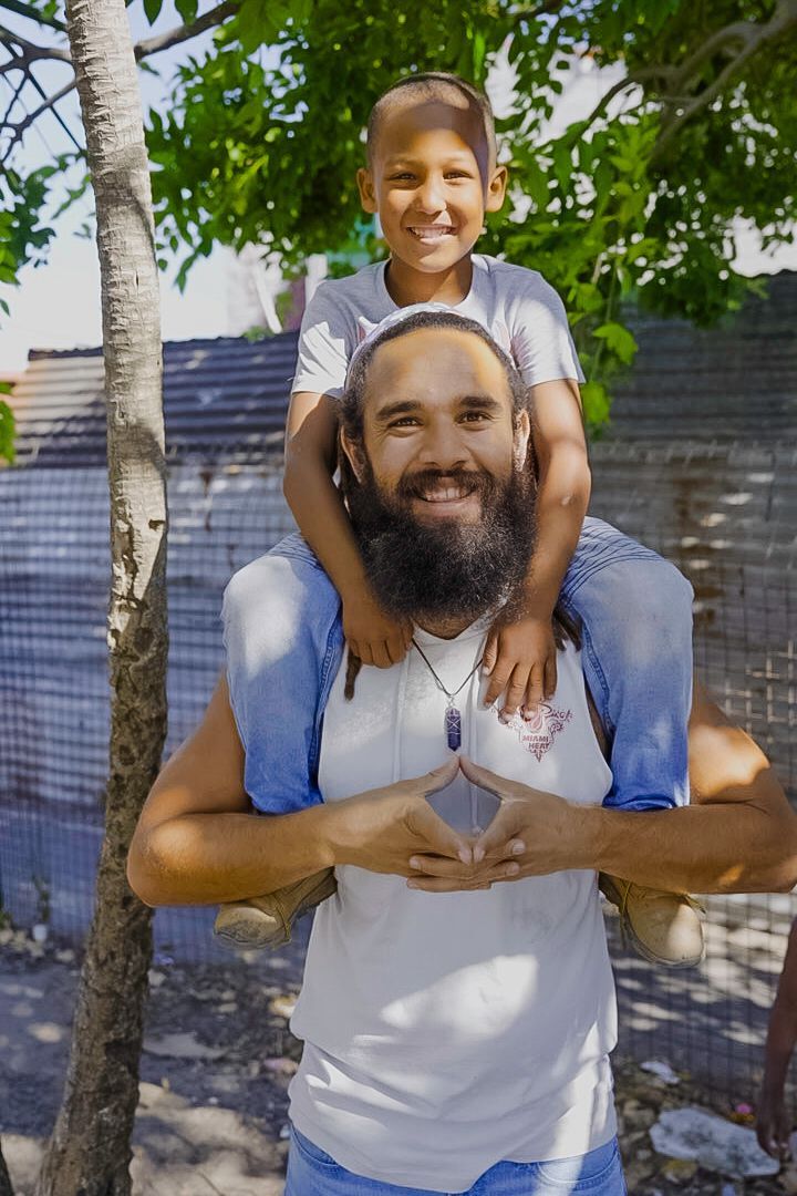 A man with a beard is carrying a little boy on his shoulders.