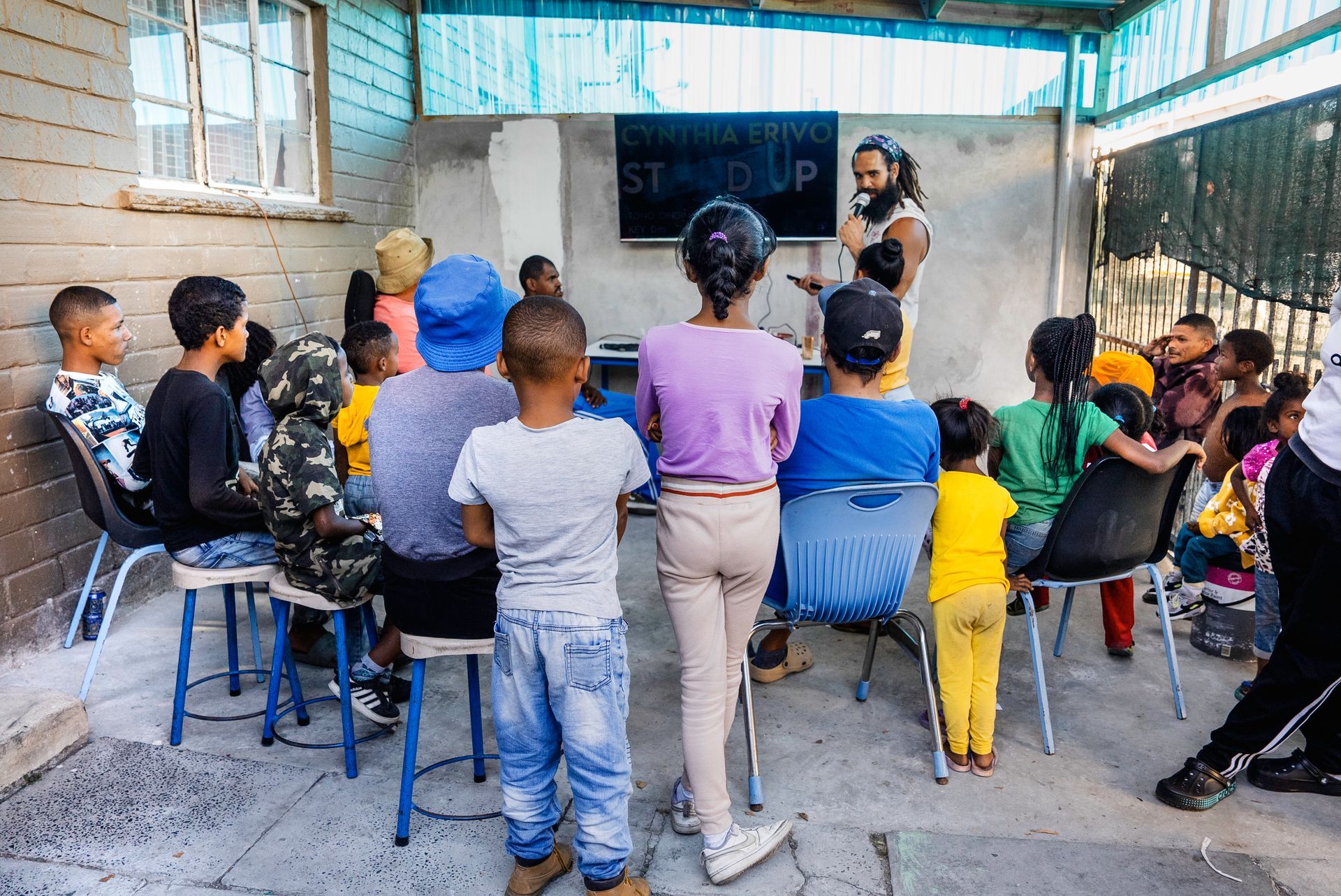 A group of people are sitting in chairs in front of a large screen.