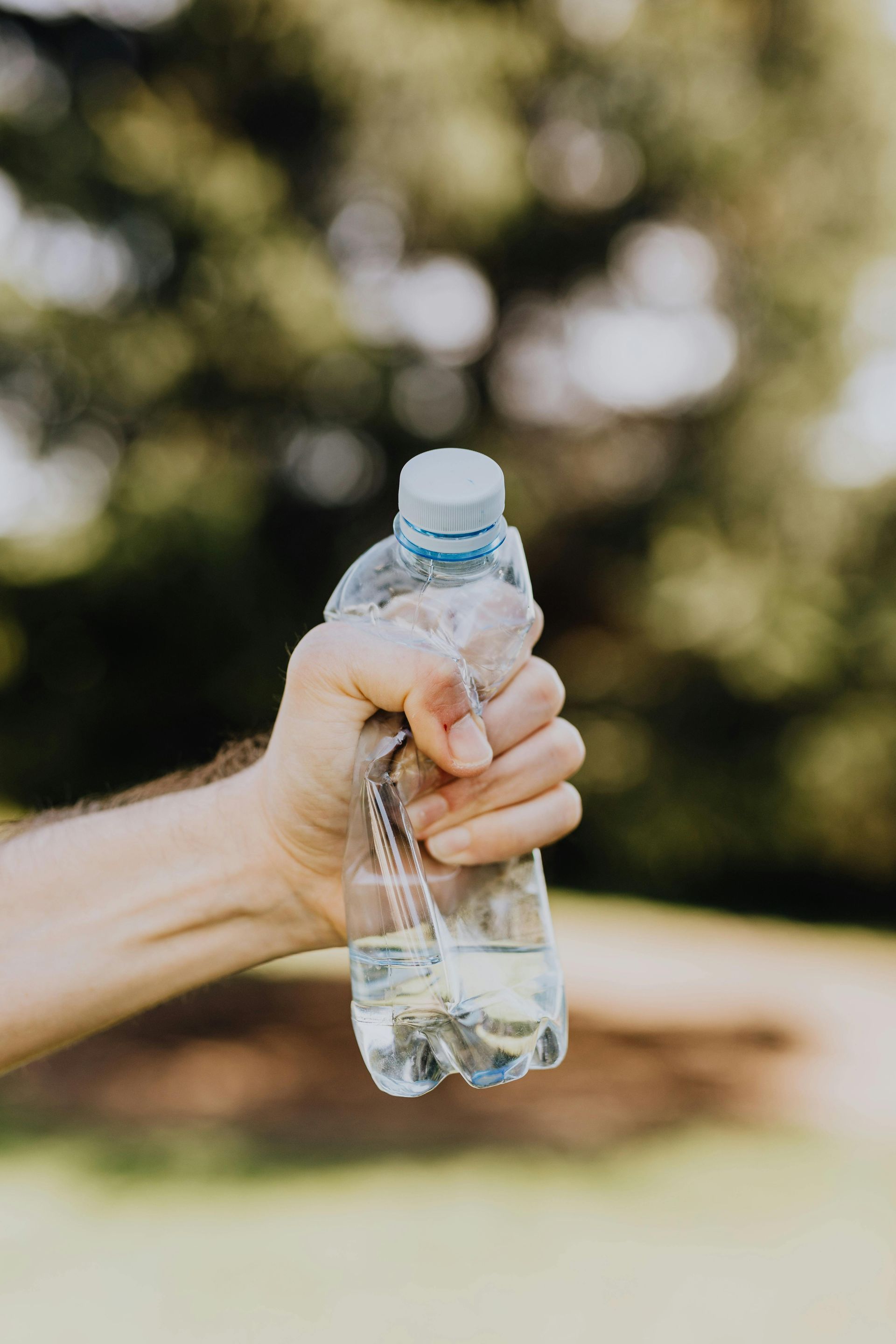 A person is holding a bottle of water in their hand.