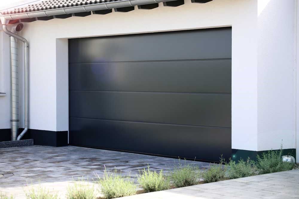 Black Garage Door is Sitting in Front of a White House — Coffs Garage Doors & Motors in Woolgoolga, NSW