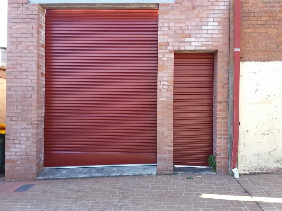 Brick Building With a Red Garage Door — Coffs Garage Doors & Motors in Woolgoolga, NSW