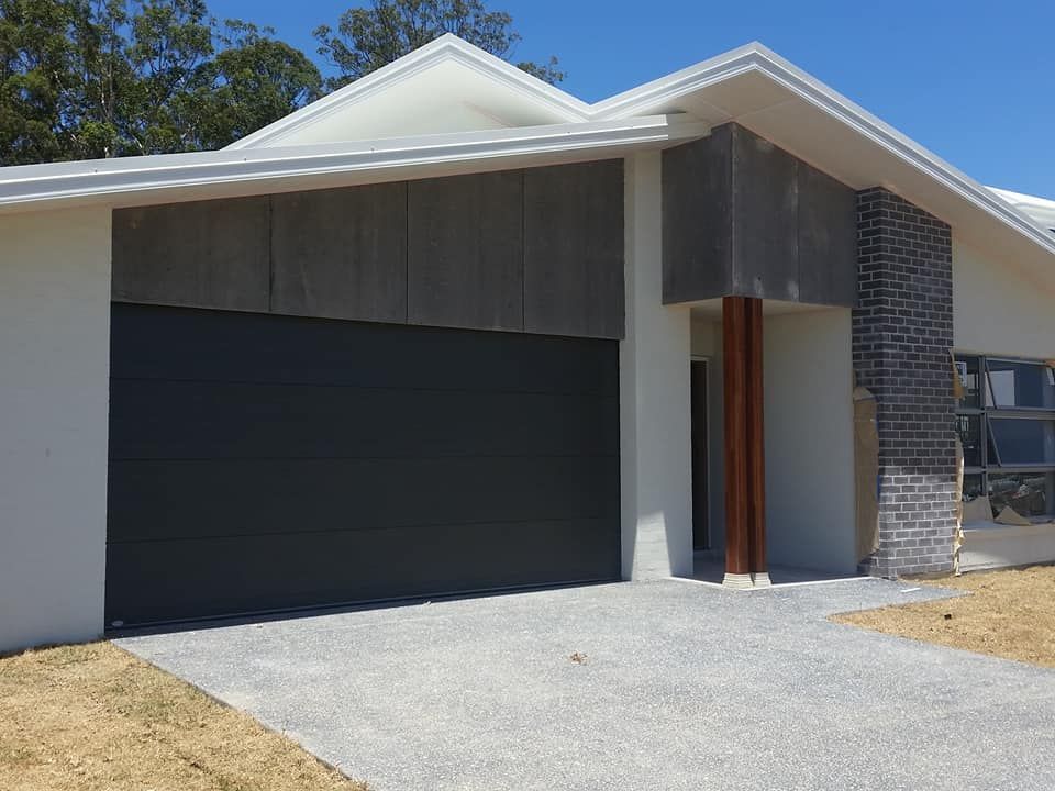 White House With a Black Garage Door and a Driveway — Coffs Garage Doors & Motors in Toormina, NSW