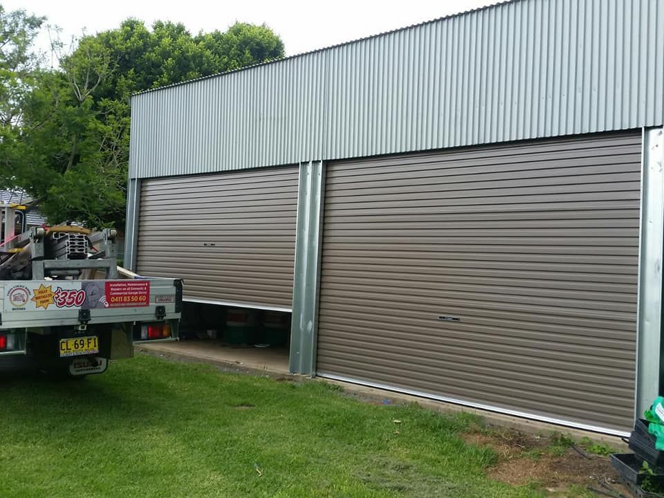 Black Garage Door is Sitting in Front of a White House — Coffs Garage Doors & Motors in Woolgoolga, NSW