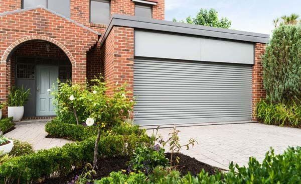Brick House With a Gray Garage Door and a Driveway — Coffs Garage Doors & Motors in Coffs Harbour, NSW