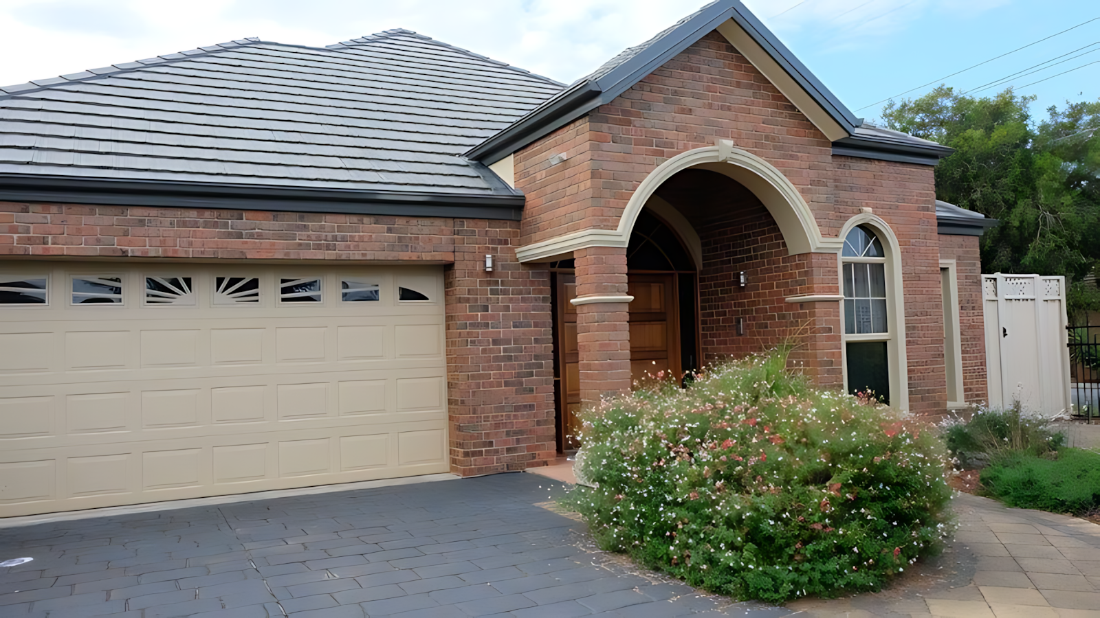 Brick House With a White Garage Door and a Bush in Front of It — Coffs Garage Doors & Motors in Bellingen, NSW