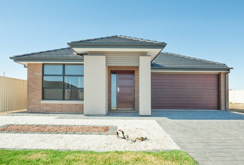 The Front of a Brick House With a Brown Garage Door — Coffs Garage Doors & Motors in Coffs Harbour, NSW