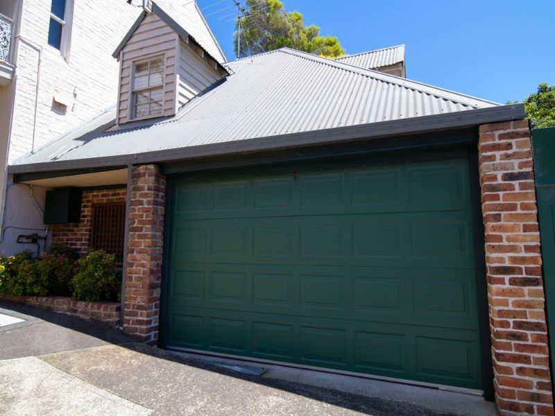House With a Green Garage Door and a Brick Wall — Coffs Garage Doors & Motors in Bellingen, NSW
