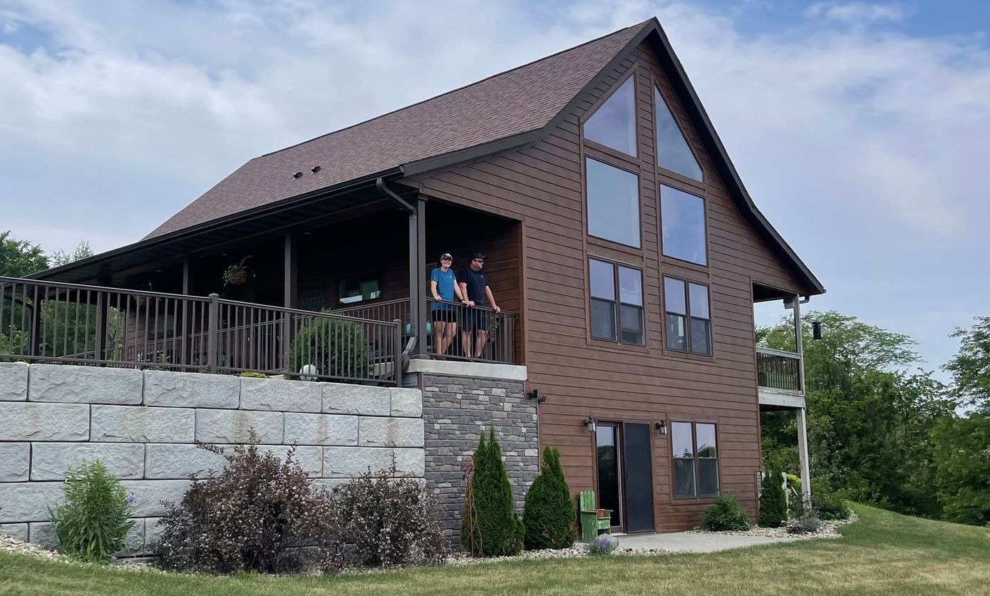 Two people standing on a porch of a large house