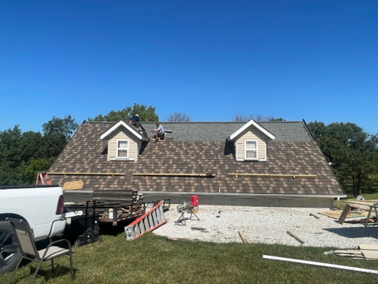 A roof is being installed on a house with a truck parked in front of it.