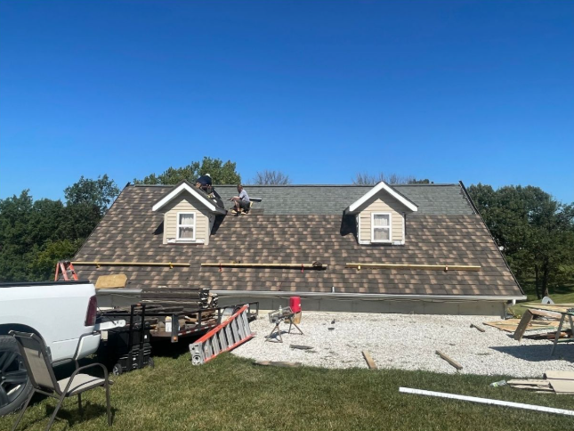 A roof is being installed on a house with a truck parked in front of it.