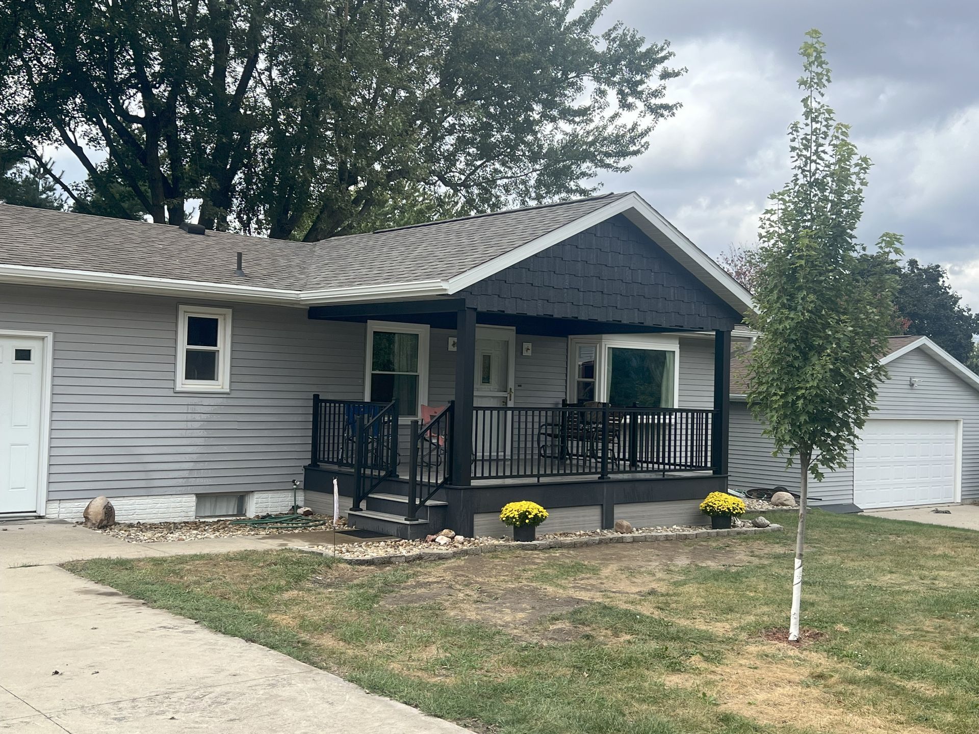 Gray house with black porch and yellow flower pots; cloudy day in Center Point, Iowa.