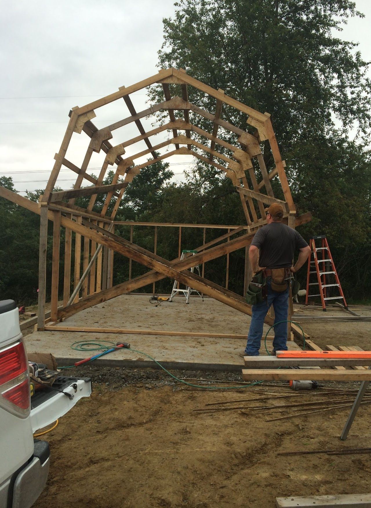 A man is standing in front of a wooden structure being built.