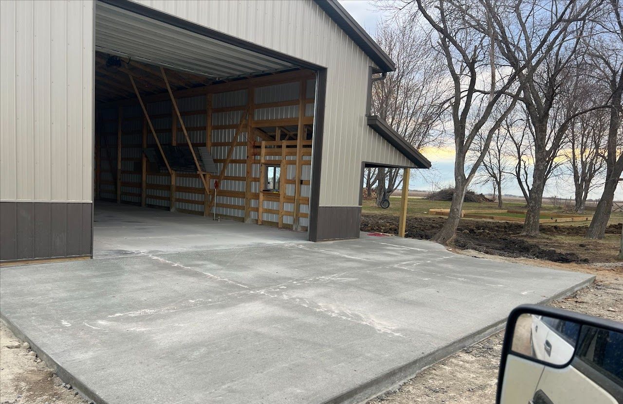 A concrete driveway is being built in front of a barn.
