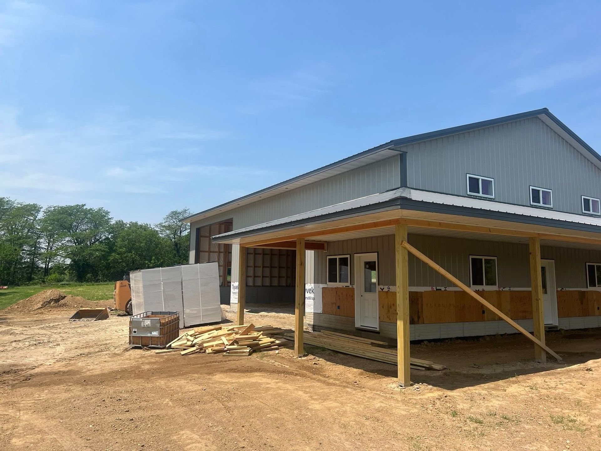 A large pole barn is being built in a dirt field.
