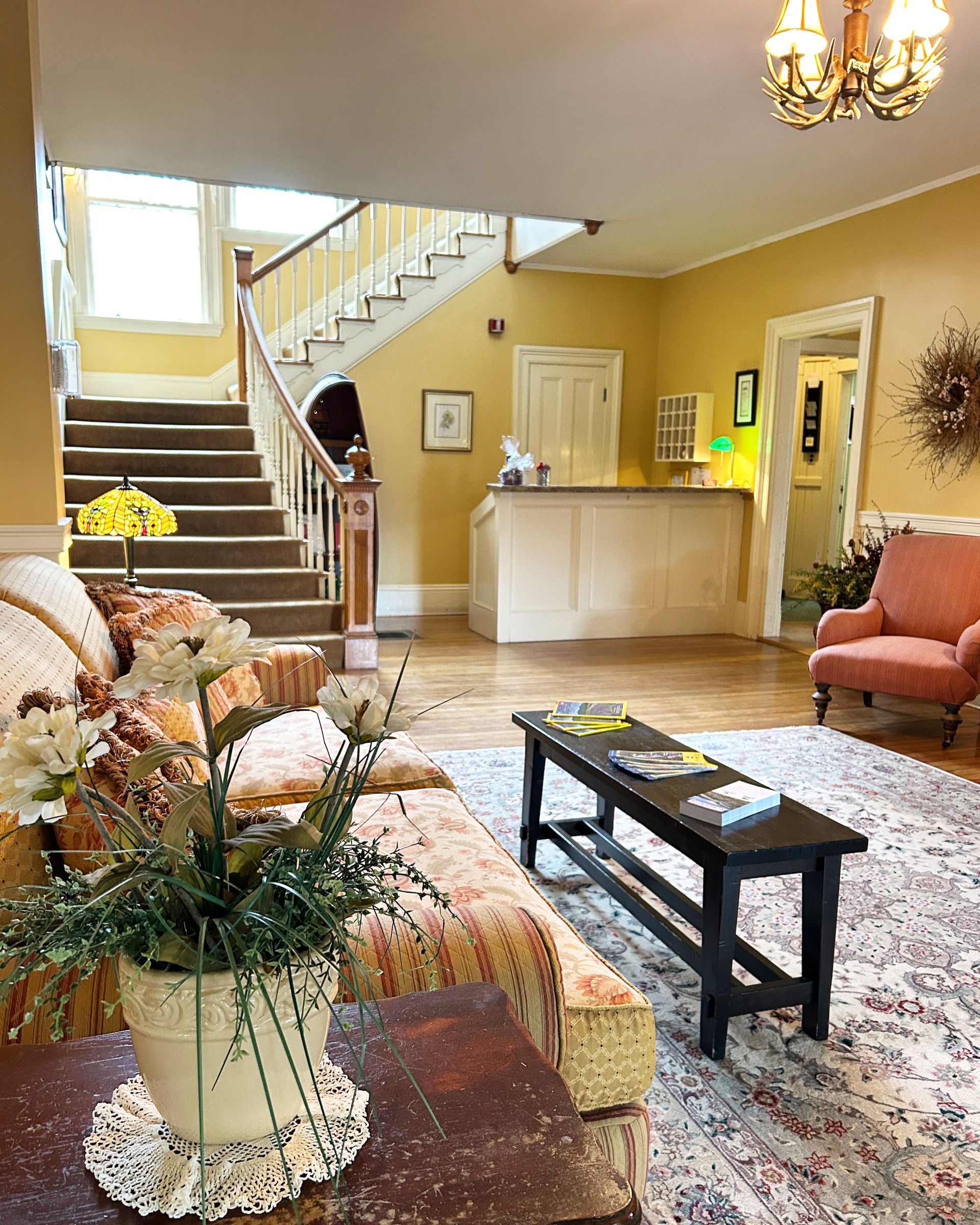 A living room with a couch , chair , table , vase of flowers and stairs.