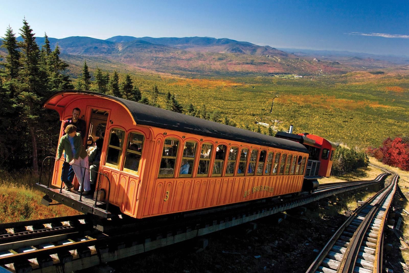 A train is going down the tracks in the mountains.