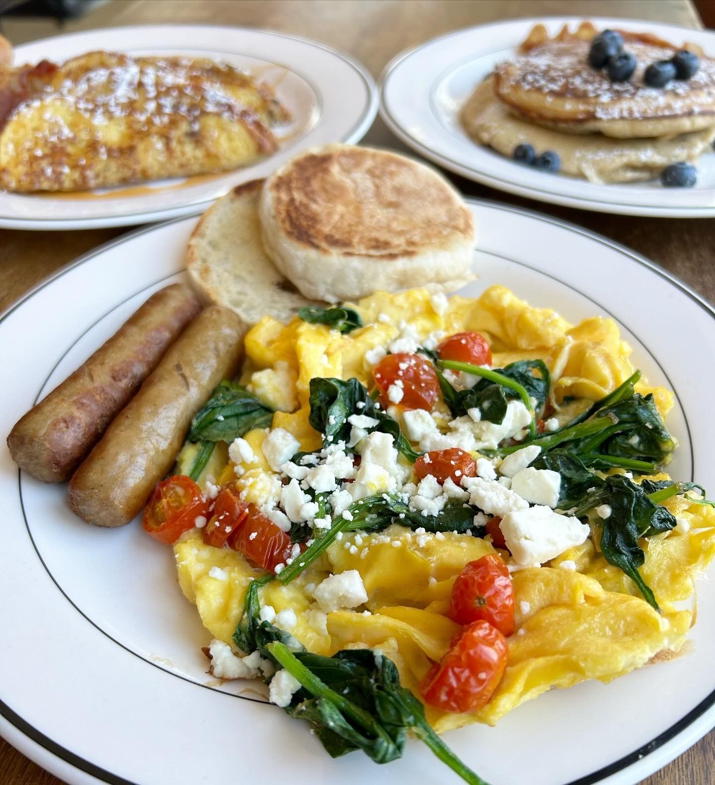 A white plate topped with scrambled eggs spinach and tomatoes