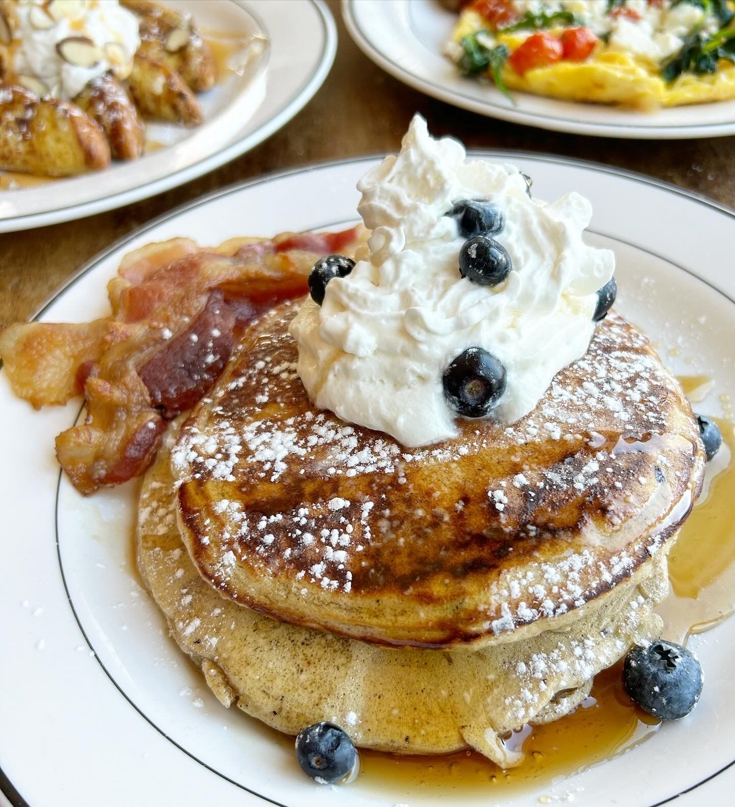 A stack of pancakes with whipped cream and blueberries on top