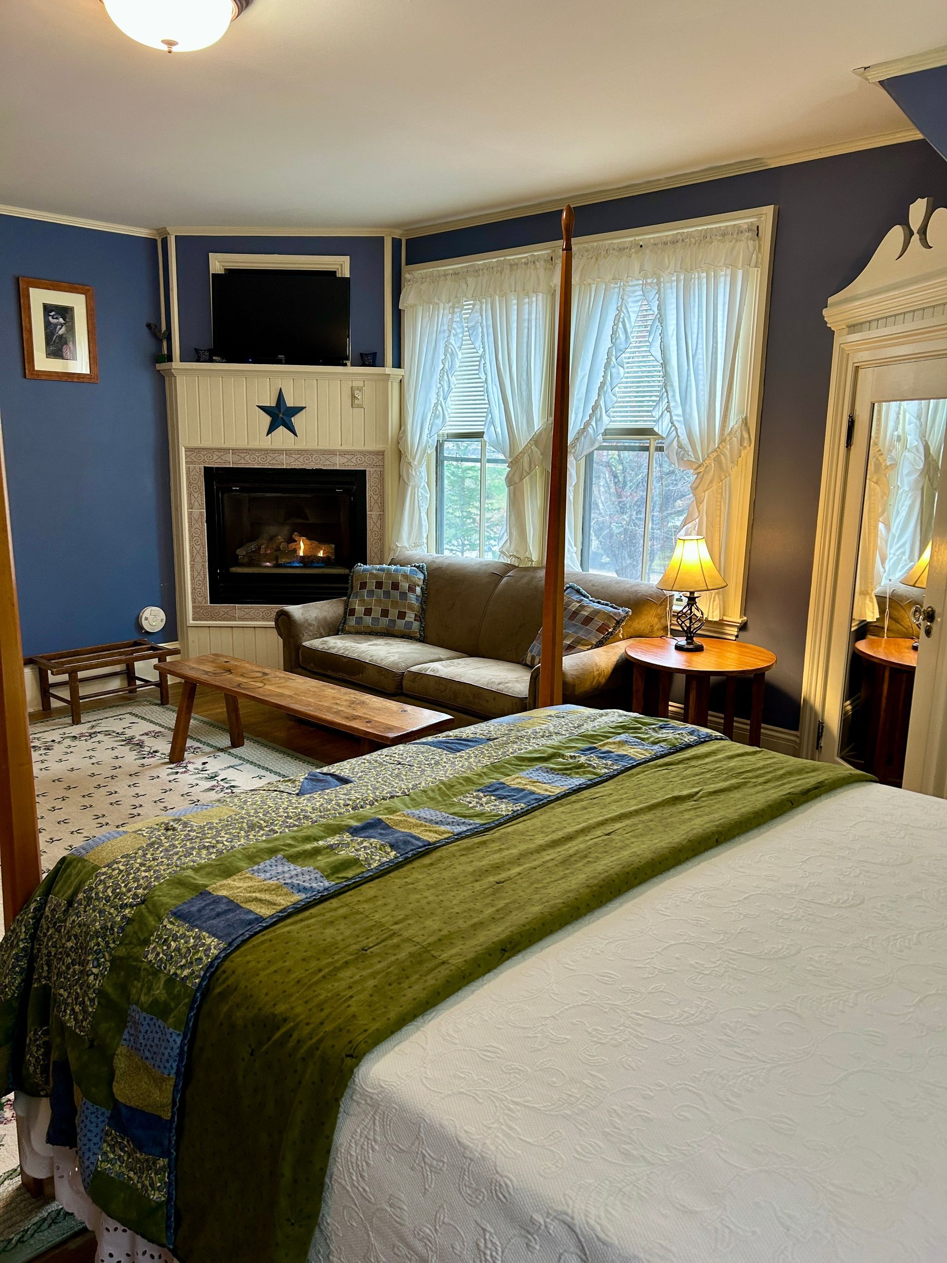 A bedroom with a bed , couch , fireplace and television.