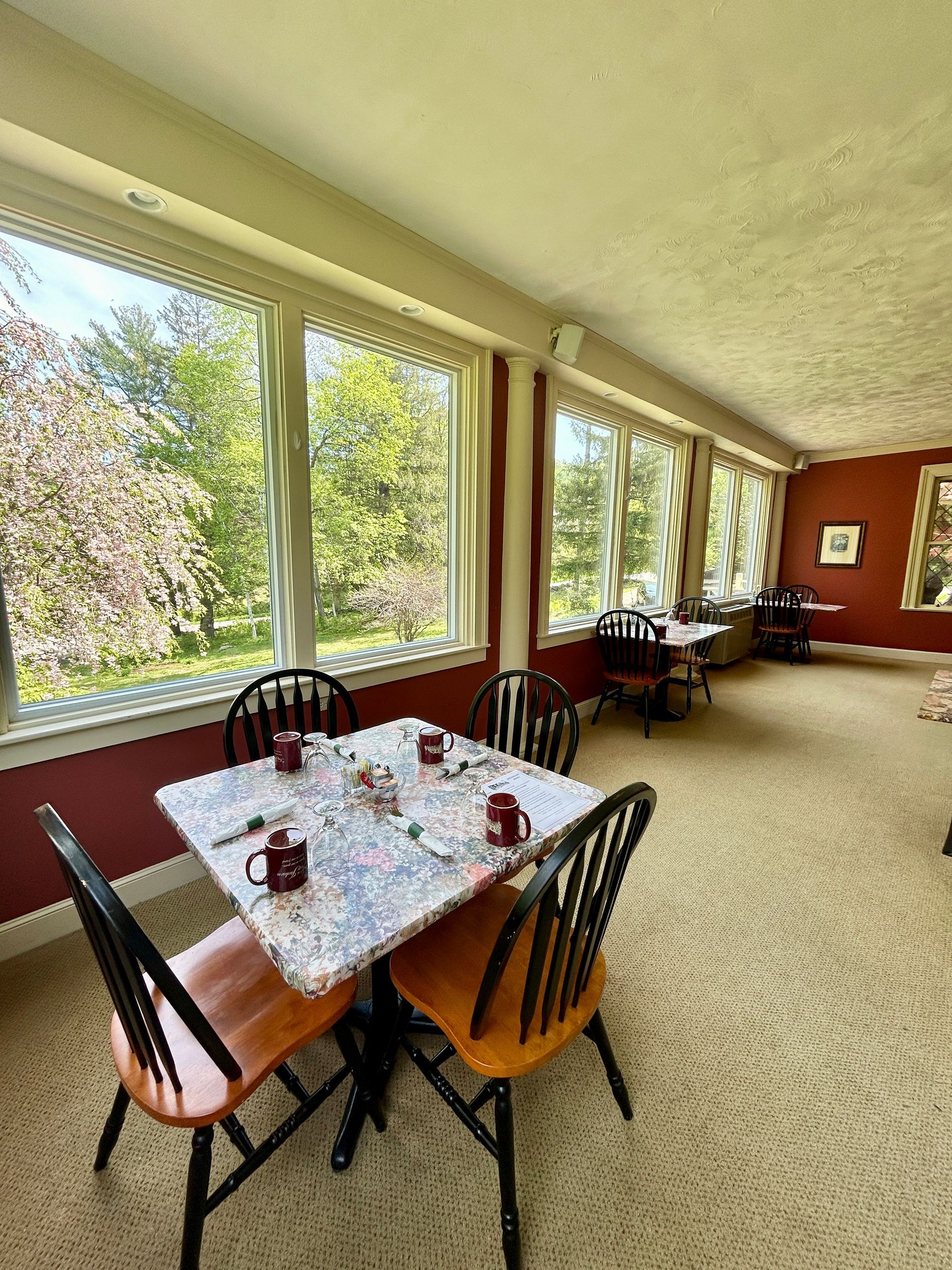 A dining room with a table and chairs and a lot of windows.