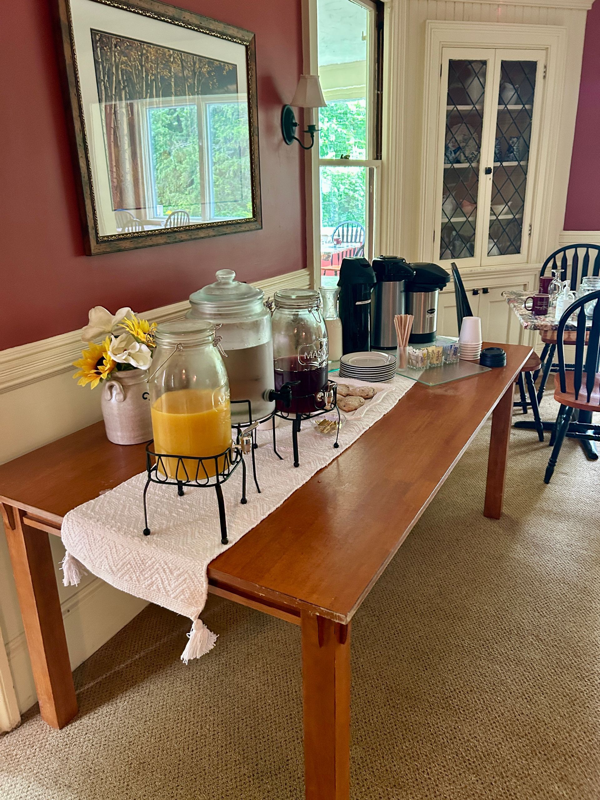 A long wooden table in a dining room with drinks on it.