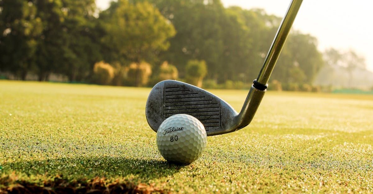 A golf club is hitting a golf ball on a golf course.