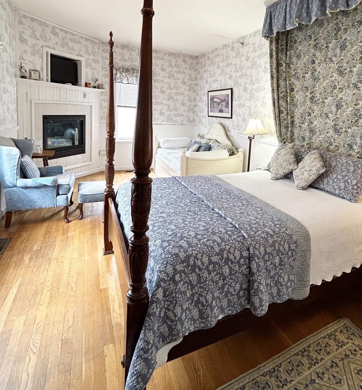 A bedroom with a four poster bed and a fireplace