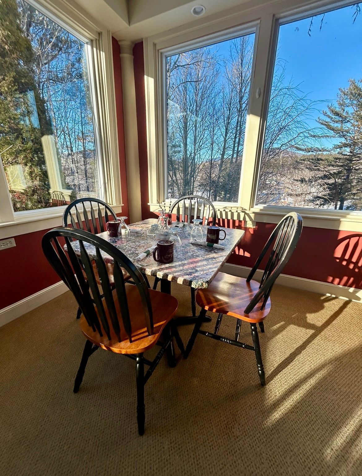 A dining room with a table and chairs in front of a window.