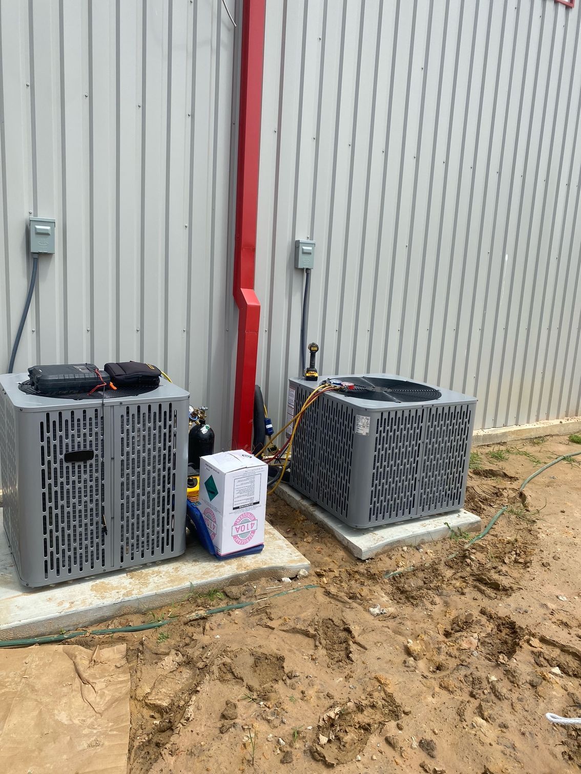 Two air conditioners are sitting outside of a building.
