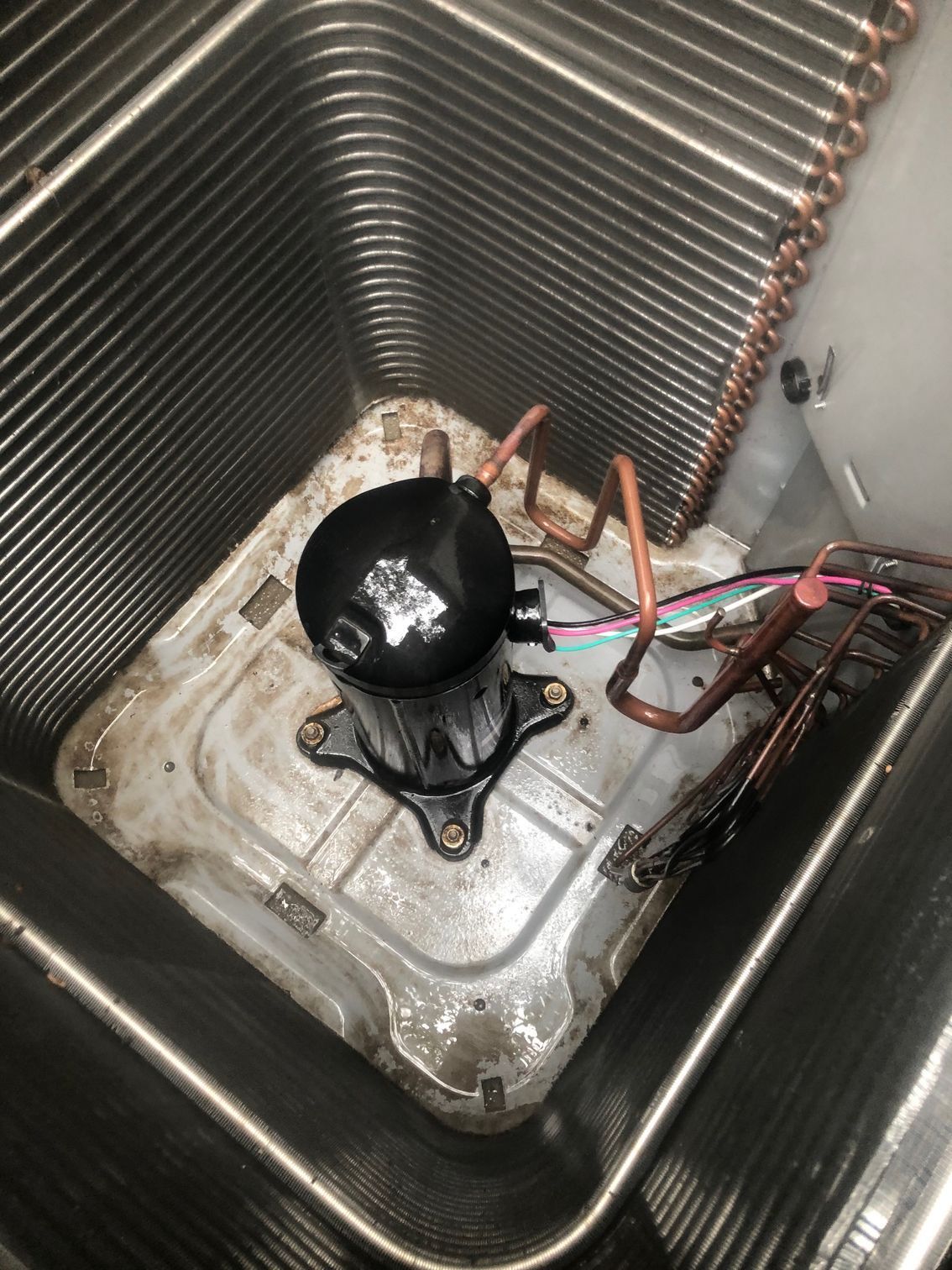 A compressor is sitting on top of a dirty air conditioner.
