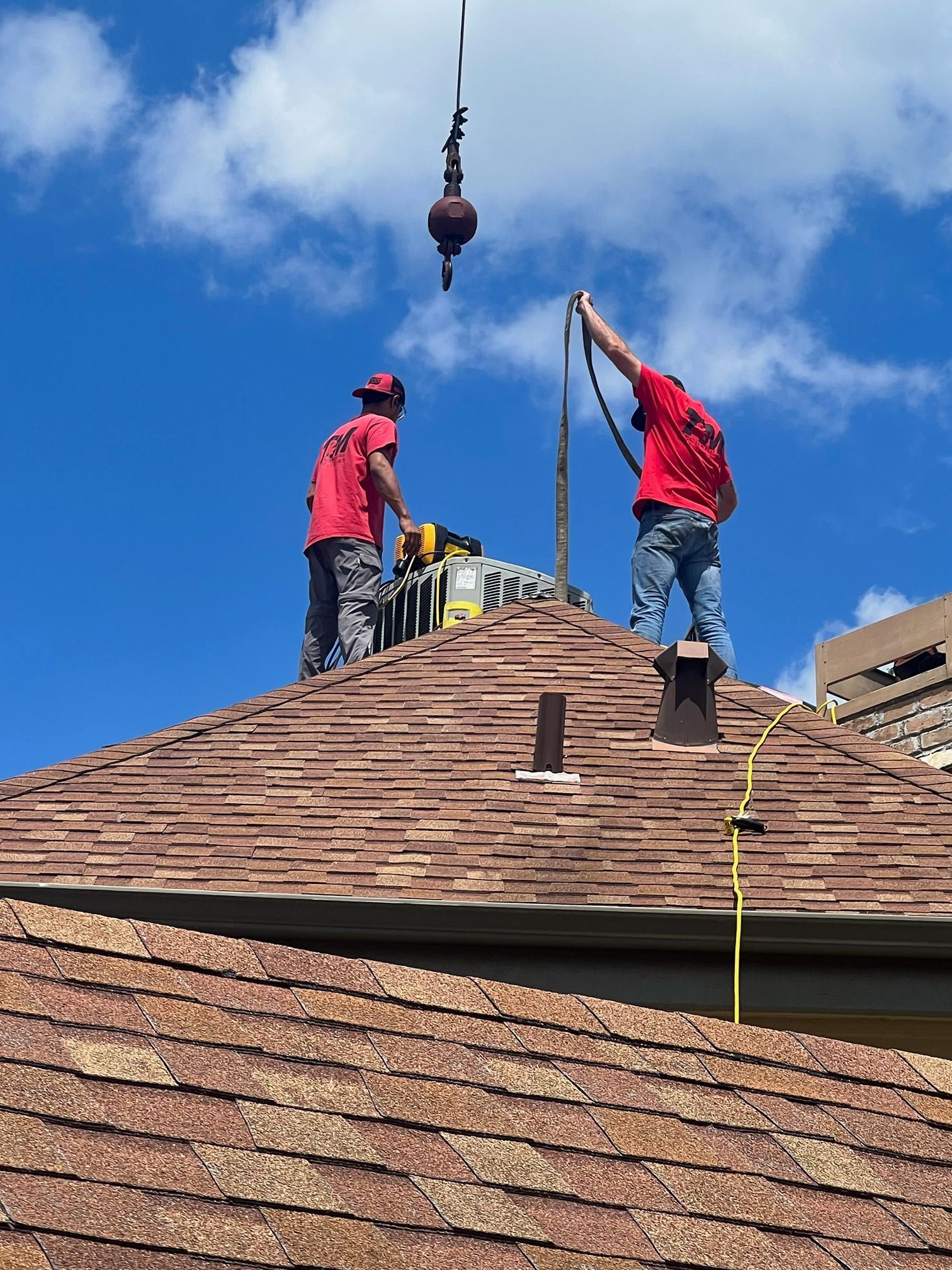 Two men are working on the roof of a house with a crane.