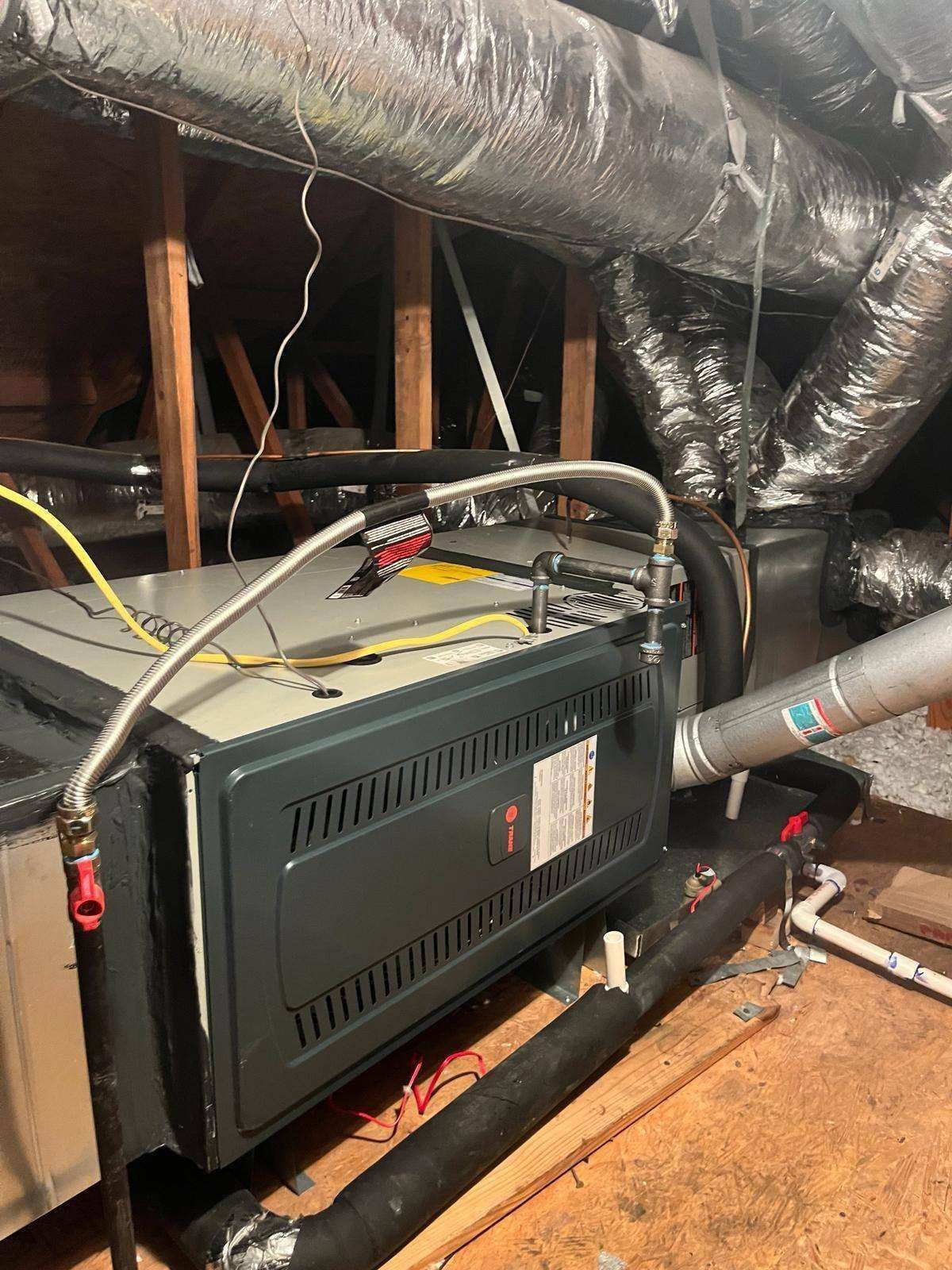 A furnace is sitting in the attic of a house.