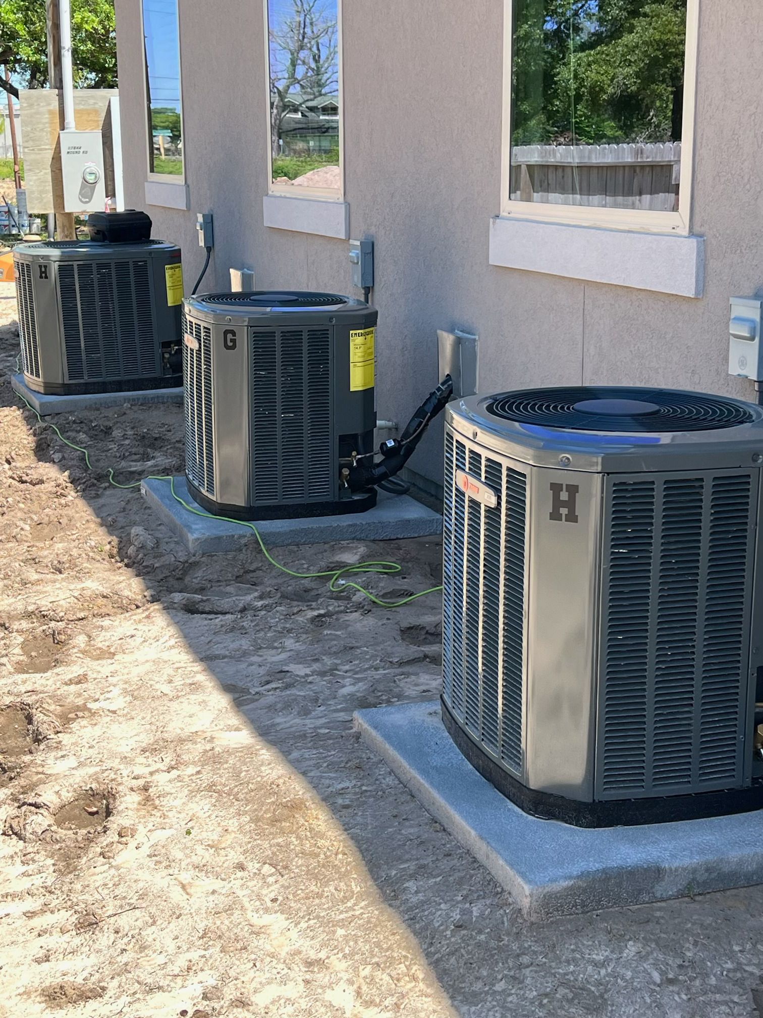 Three air conditioners are sitting outside of a building.