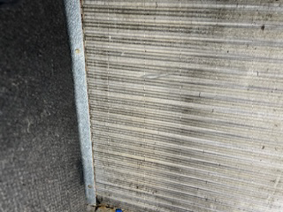 A close up of a dirty radiator on a wall.