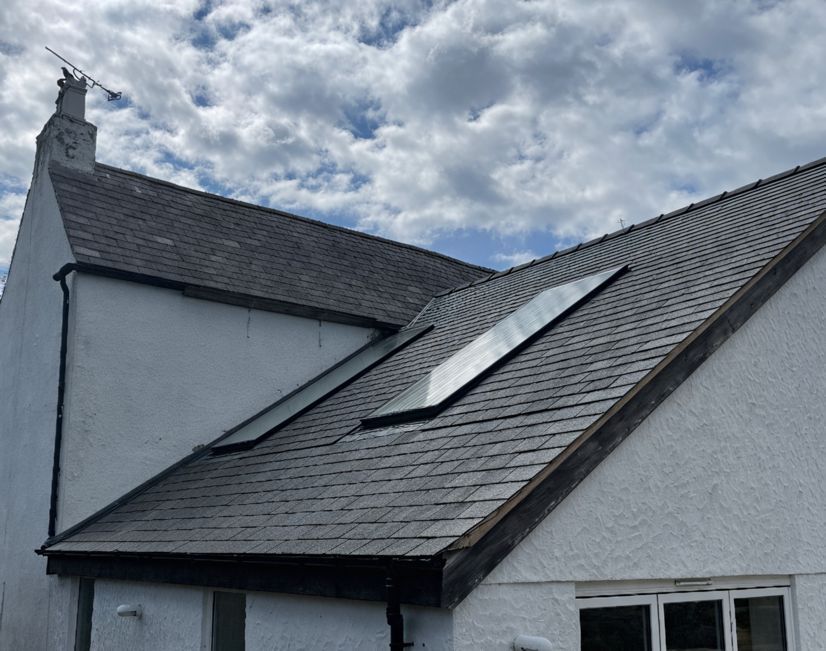 A white house with a slate roof and a skylight