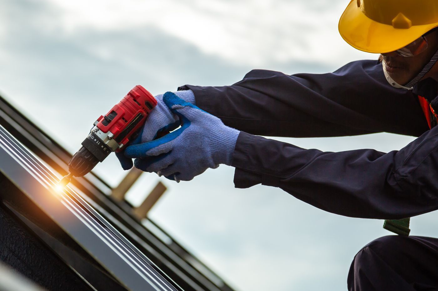 A man is working on a roof with a drill.