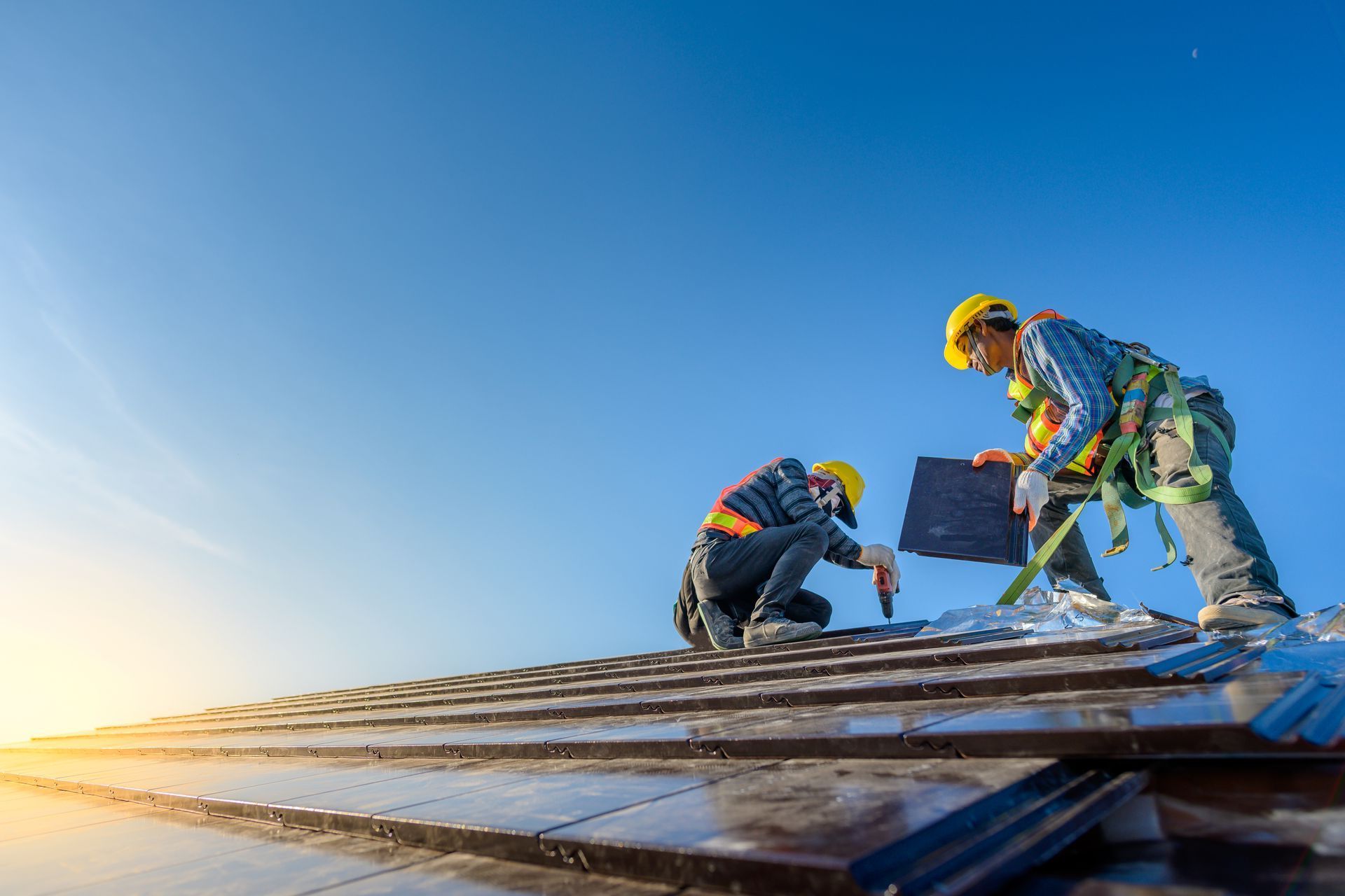 Two construction workers are working on a roof.