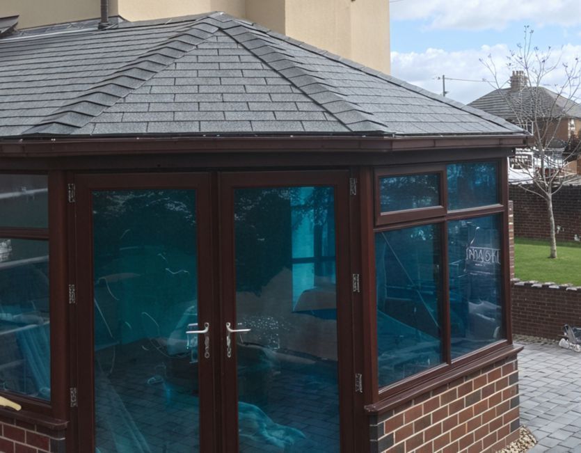 A conservatory with a slate roof and blue glass doors