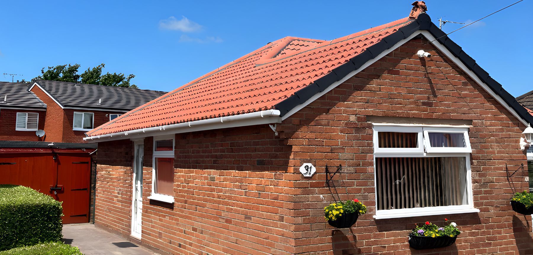 A small brick house with a red tiled roof