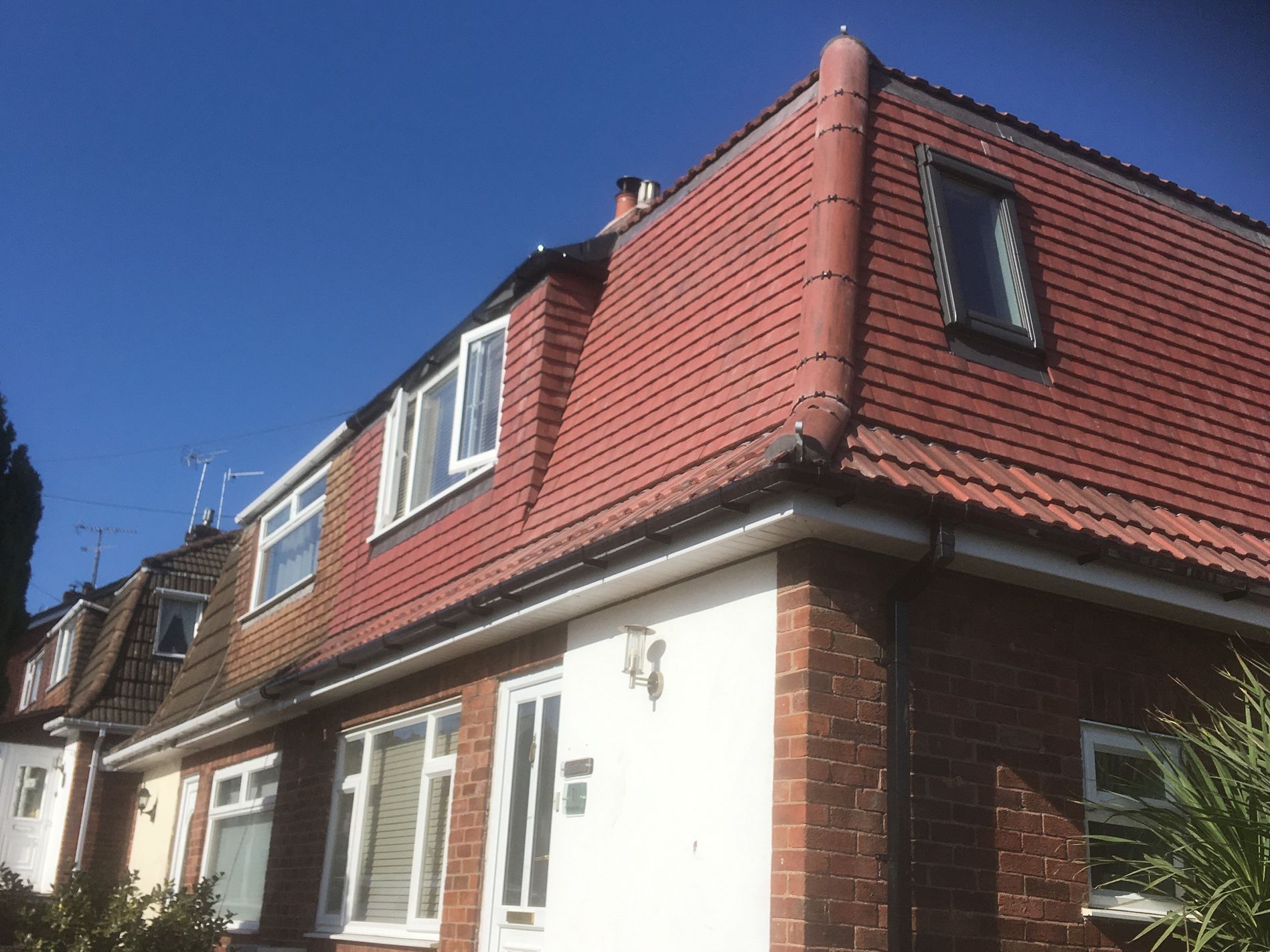 A brick house with a red roof and a white door.