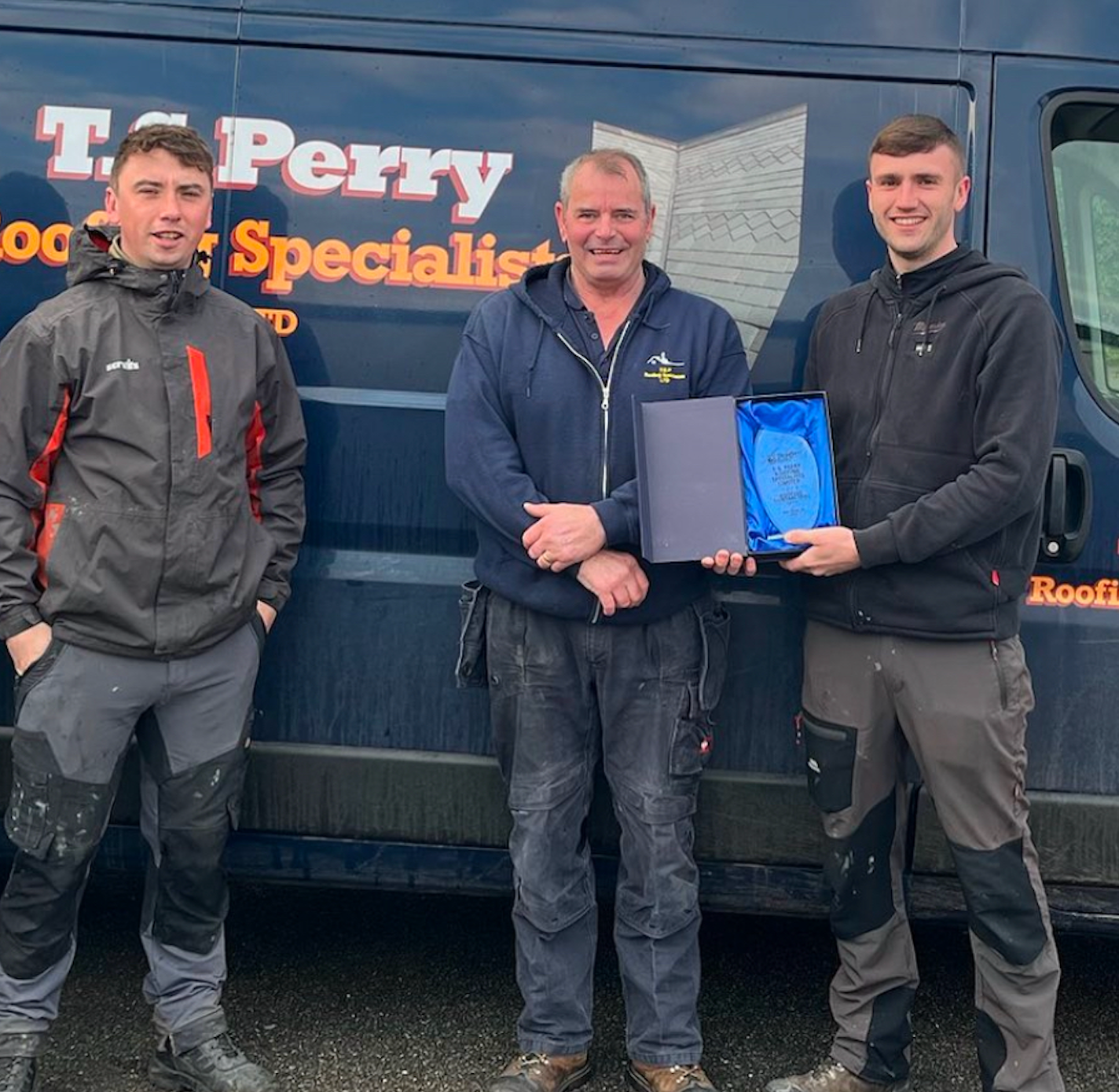 Three men standing in front of a van that says t. perry specialist