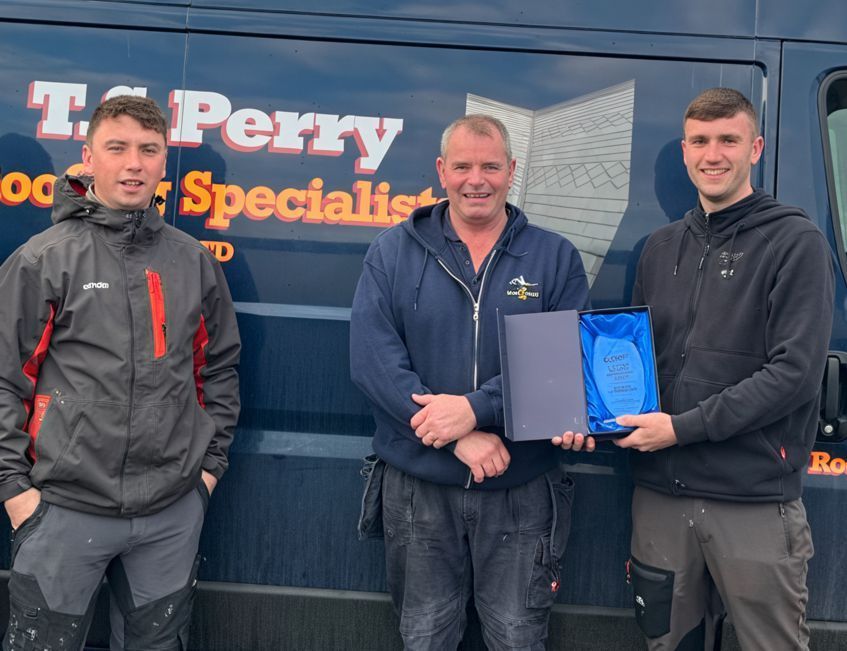 Three men are standing in front of a van that says t. perry